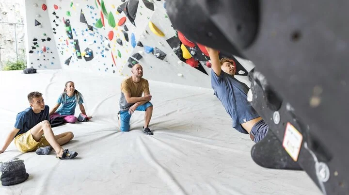 Ein Mann beim Bouldern, im Hintergrund warten weitere Personen, bis sie an der Reihe sind | © DAV / Jens Klatt