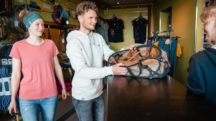 Zwei Personen leihen sich in einer Boulderhalle Ausrüstung aus. | © DAV/Marisa Koch