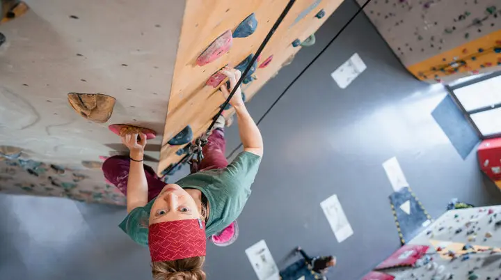 Eine Frau klettert in einer Kletterhalle, ihr Partner sichert sie. | © DAV/Marisa Koch